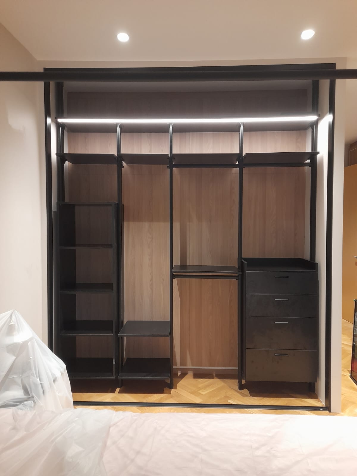 Wall-mounted pole system wardrobe in a compact bedroom