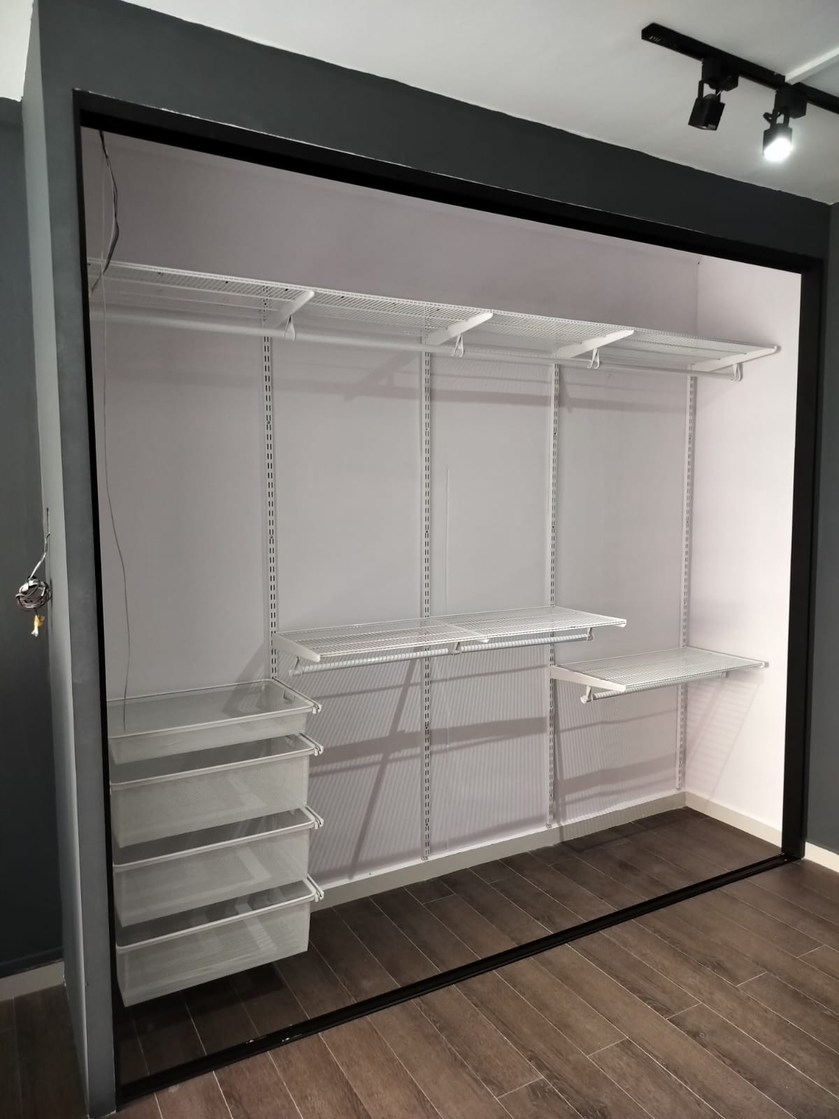 Actual site photo of a completed white HausFlex metal wardrobe with sliding doors brightening a Singapore bedroom.